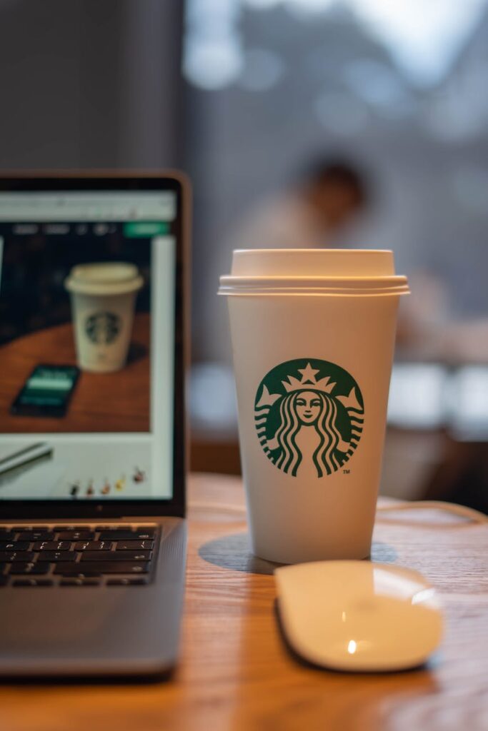 starbucks coffee on a wooden table beside a laptop