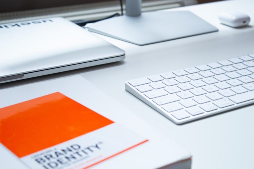 laptop, keyboard, and a brand identity book to decide on full rebranding vs. brand refresh