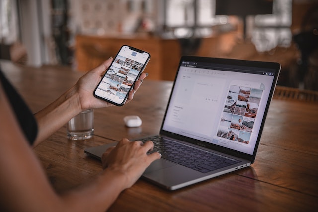 A person using social media on a smartphone and on a laptop at the same time