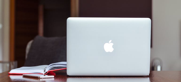 an Apple laptop and a notebook on the table