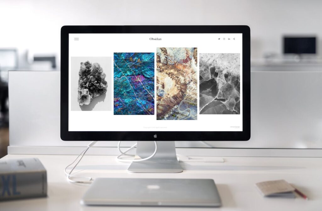 An iMac screen with colorful images near a MacBook
