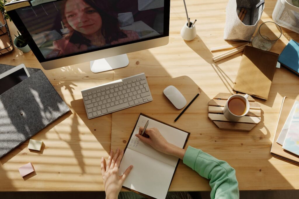A person on a Zoom call writing down web design tips for wellness brands