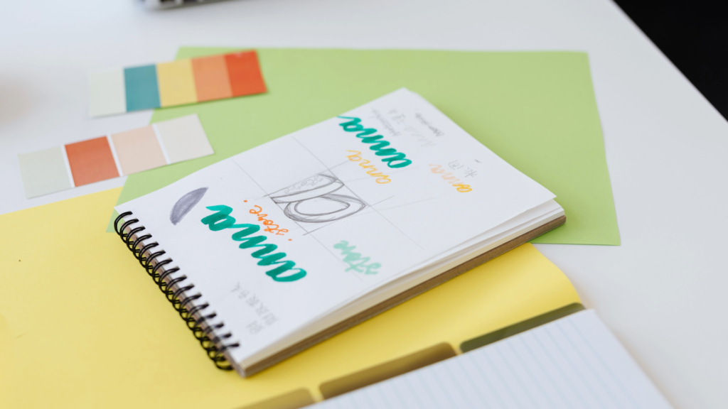 Printed branding proposal document with design swatches and a pen